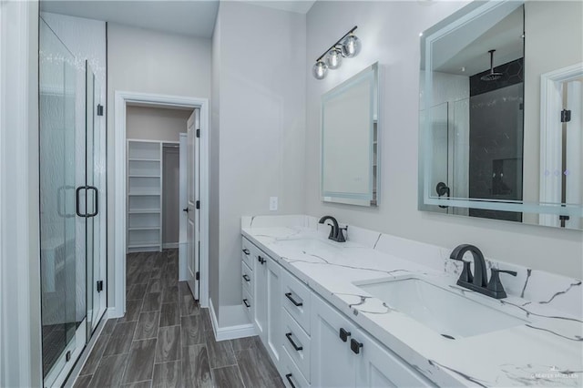 bathroom featuring a stall shower, wood finish floors, a sink, and a spacious closet