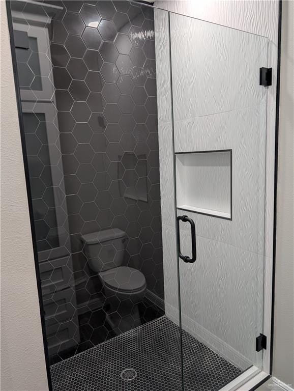 full bathroom featuring toilet, a shower stall, and tile patterned floors