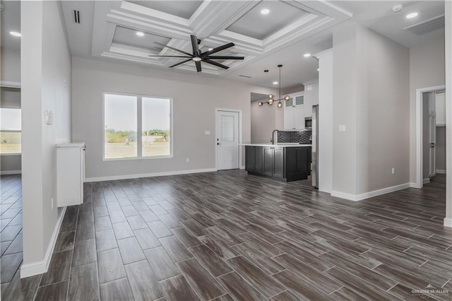 unfurnished living room featuring ceiling fan with notable chandelier, wood finish floors, a sink, and visible vents