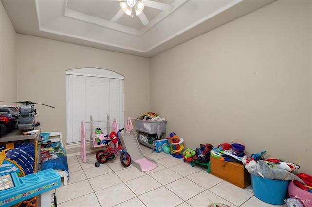 rec room with a tray ceiling, ceiling fan, and light tile patterned flooring