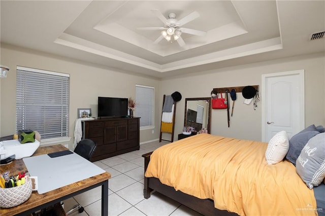 bedroom with ceiling fan, light tile patterned floors, and a tray ceiling