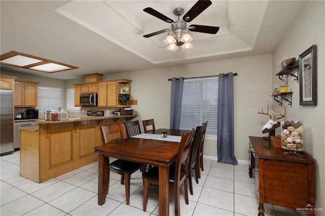 dining room with a raised ceiling, ceiling fan, and light tile patterned flooring