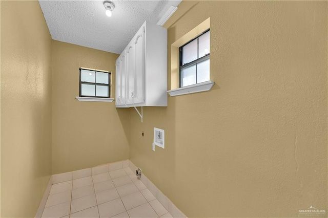 laundry room with electric dryer hookup, cabinets, a healthy amount of sunlight, and a textured ceiling