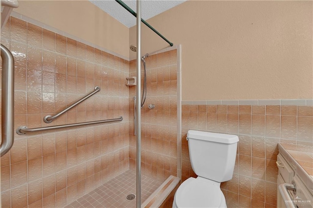 bathroom featuring a textured ceiling, toilet, vanity, a shower with shower door, and tile walls