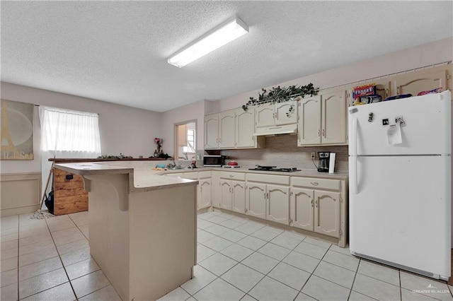 kitchen featuring tasteful backsplash, black gas stovetop, a textured ceiling, white refrigerator, and light tile patterned flooring