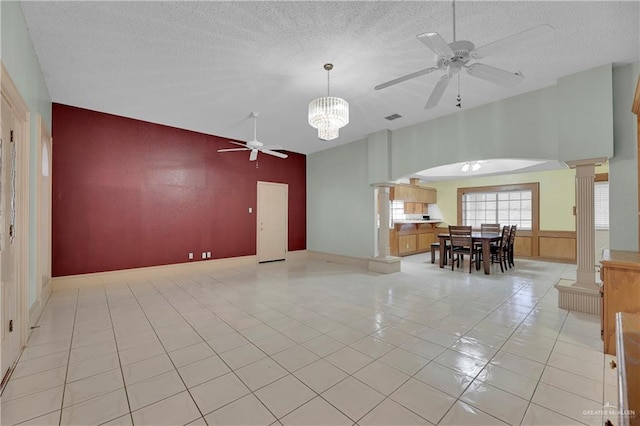 unfurnished living room with light tile patterned flooring, a textured ceiling, a high ceiling, and decorative columns