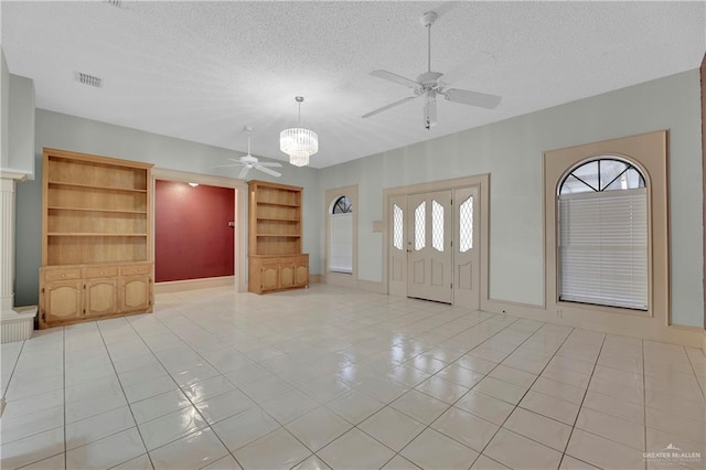 tiled foyer featuring ceiling fan with notable chandelier and a textured ceiling