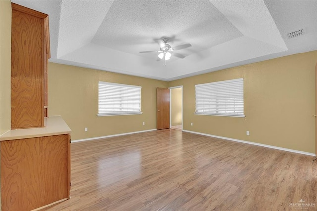 unfurnished living room featuring a tray ceiling, ceiling fan, wood-type flooring, and a textured ceiling