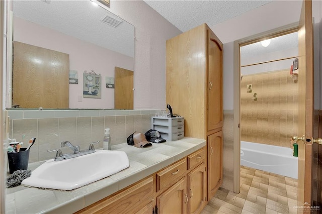 bathroom featuring shower / bathing tub combination, decorative backsplash, a textured ceiling, and vanity