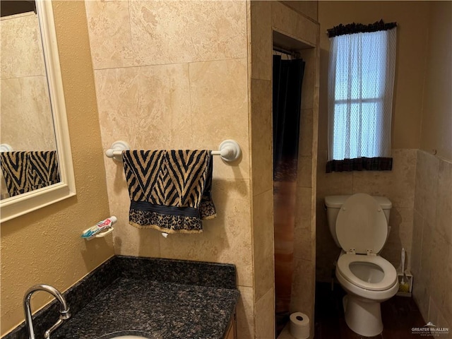 bathroom featuring vanity, toilet, and tile walls