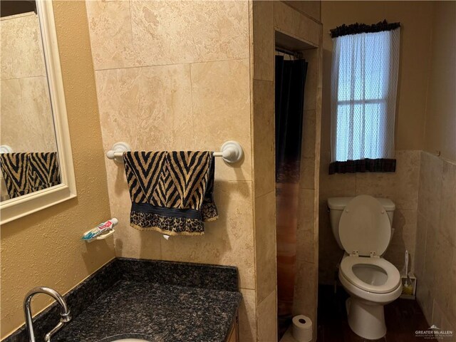 bathroom featuring vanity, toilet, and tile walls