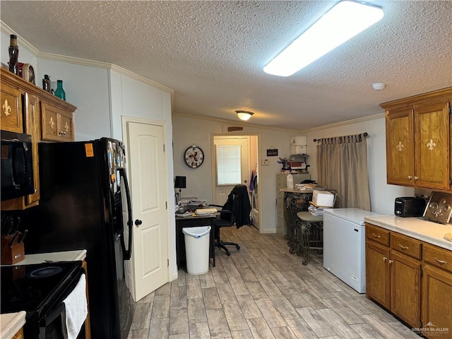 kitchen featuring black appliances, crown molding, light wood-type flooring, and a textured ceiling