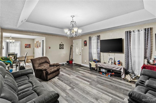 living room featuring hardwood / wood-style flooring, a notable chandelier, a raised ceiling, and a textured ceiling