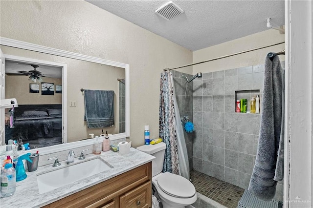 bathroom featuring vanity, ceiling fan, toilet, a textured ceiling, and walk in shower