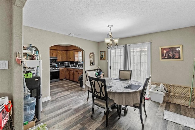 dining area featuring an inviting chandelier, a textured ceiling, and hardwood / wood-style flooring