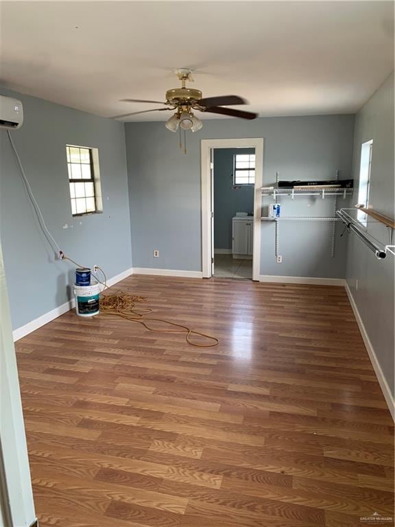 interior space featuring ceiling fan, wood-type flooring, and a wall unit AC