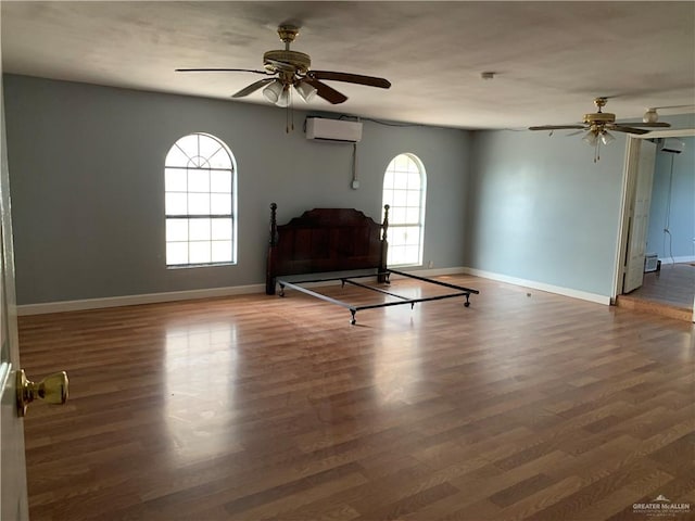 unfurnished room with a wall mounted AC, ceiling fan, a healthy amount of sunlight, and dark hardwood / wood-style floors