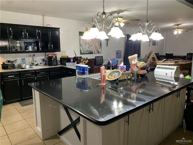 kitchen featuring sink, a spacious island, pendant lighting, light tile patterned floors, and ceiling fan with notable chandelier