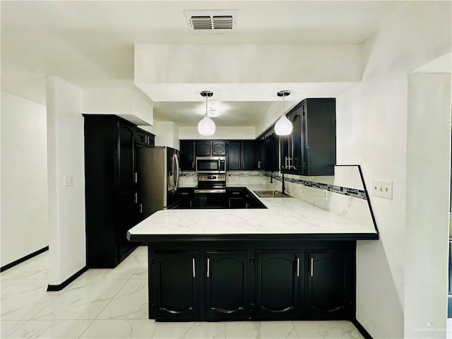 kitchen featuring sink, hanging light fixtures, stainless steel appliances, tasteful backsplash, and kitchen peninsula