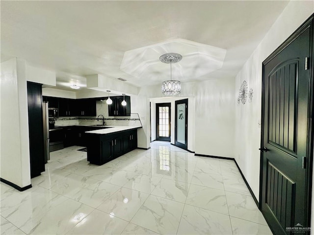 kitchen featuring sink, decorative light fixtures, a kitchen island, a notable chandelier, and backsplash