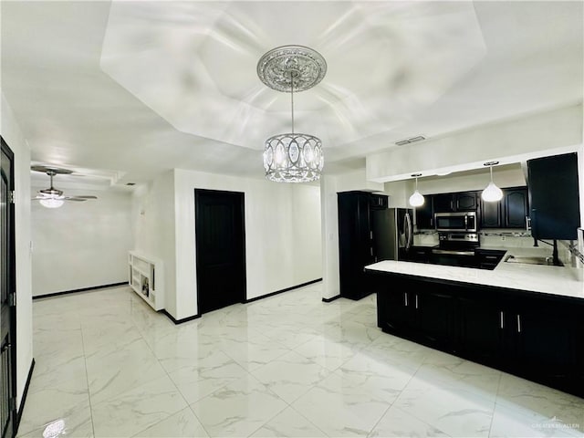 kitchen featuring pendant lighting, sink, stainless steel appliances, heating unit, and ceiling fan with notable chandelier