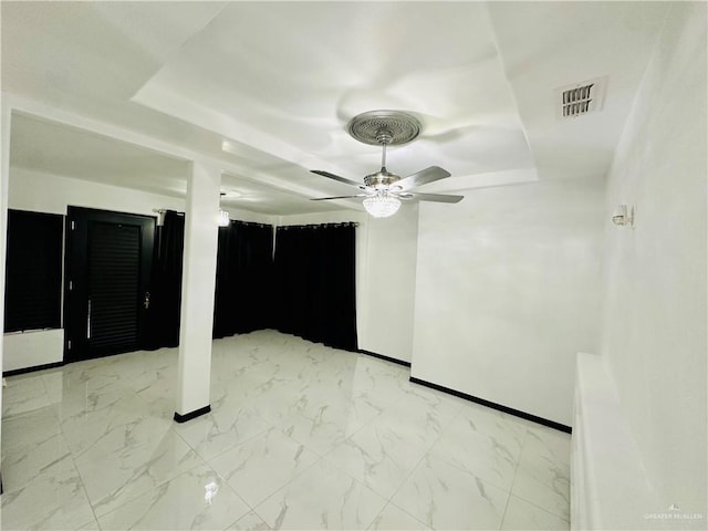 empty room featuring a raised ceiling and ceiling fan