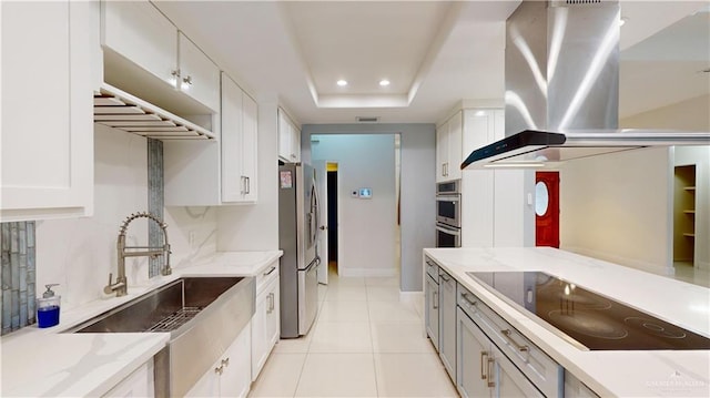 kitchen with sink, black electric stovetop, island range hood, white cabinets, and a raised ceiling