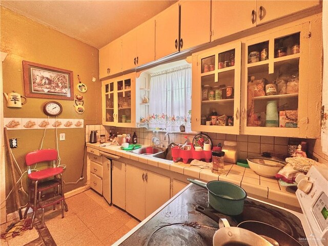 kitchen featuring tile countertops, decorative backsplash, and sink