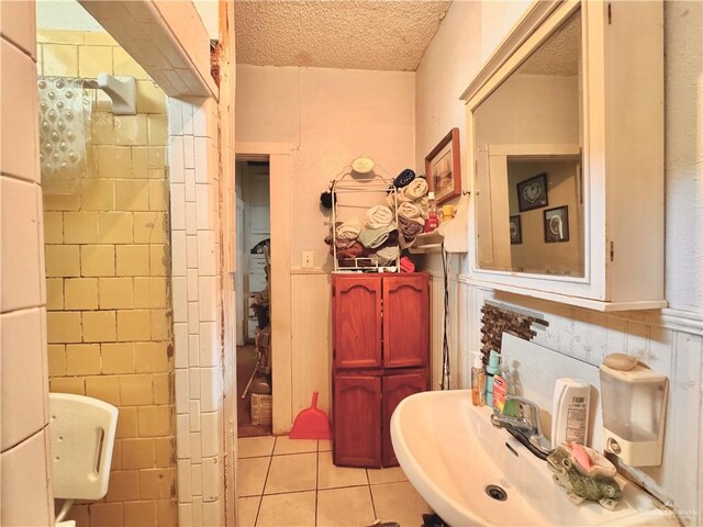 bathroom featuring tile patterned floors, a textured ceiling, and tile walls