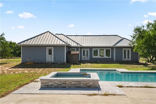 35206 Longhorn Dr, Linn, TX 78563 - rear view of house with french doors, an in-ground hot tub, an outdoor pool, metal roof, and a yard