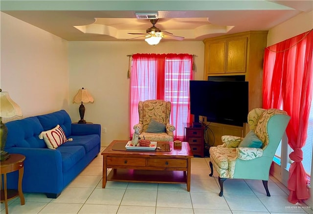 tiled living room featuring a raised ceiling and ceiling fan