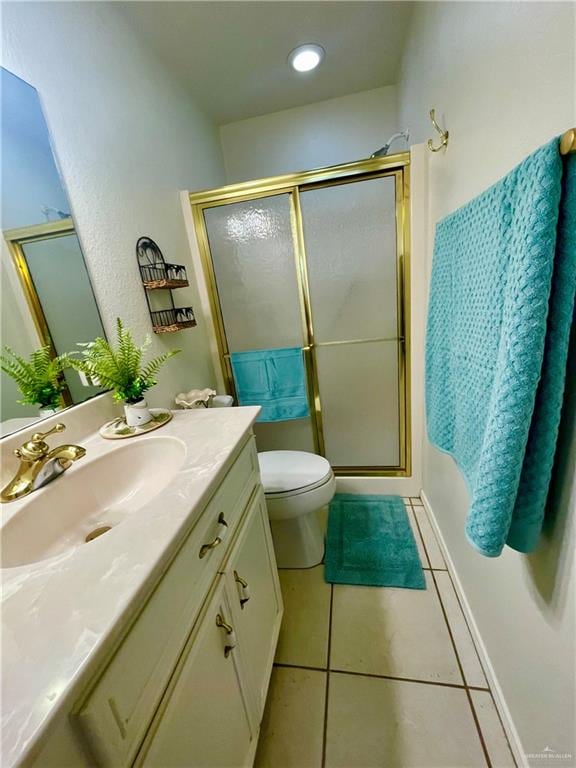 bathroom with toilet, tile patterned flooring, vanity, and walk in shower