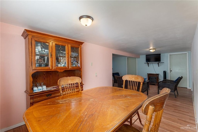 dining space featuring light wood-type flooring and a fireplace