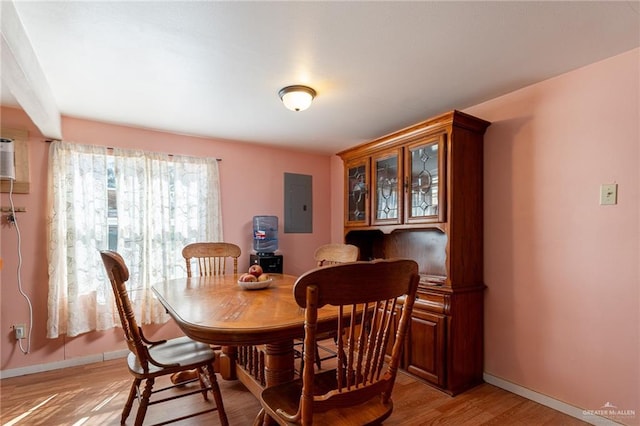 dining area with light wood-style floors, electric panel, and baseboards