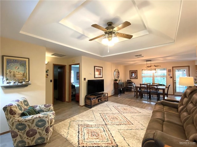 living room with hardwood / wood-style floors, a tray ceiling, and ceiling fan