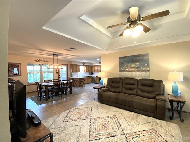 living room featuring hardwood / wood-style flooring, ceiling fan, and a tray ceiling