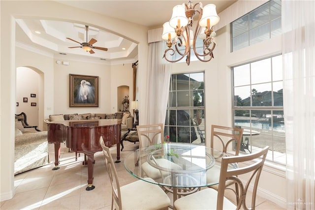 dining room featuring ceiling fan with notable chandelier, light tile patterned flooring, crown molding, and a tray ceiling