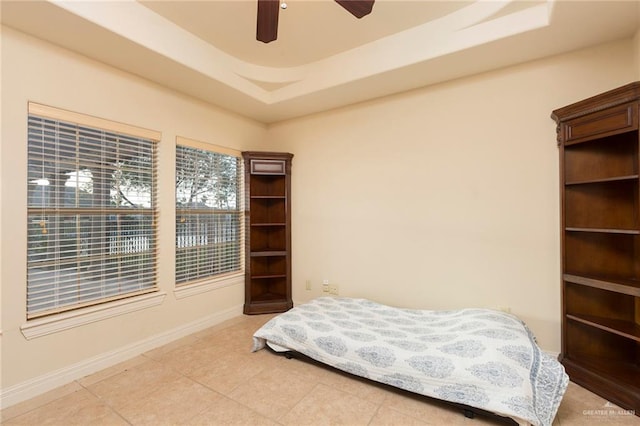 tiled bedroom with a tray ceiling and ceiling fan