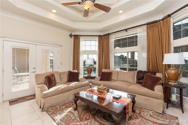 tiled living room featuring ceiling fan, a raised ceiling, crown molding, and french doors