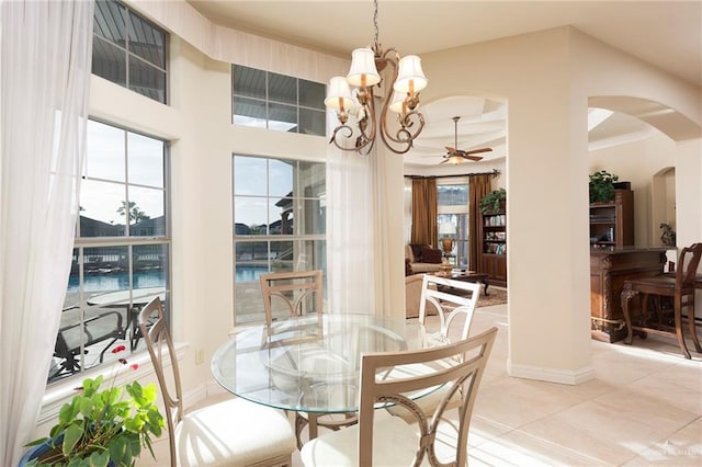 tiled dining area with a water view, a healthy amount of sunlight, ceiling fan with notable chandelier, and ornamental molding