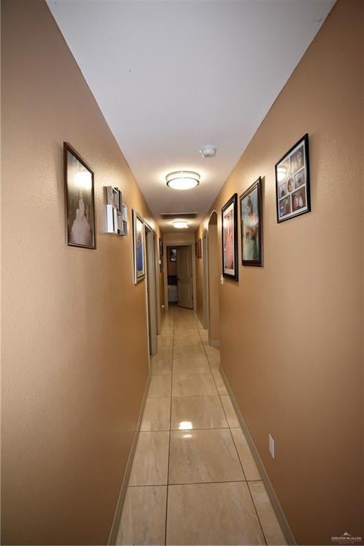 hallway with light tile patterned floors and baseboards