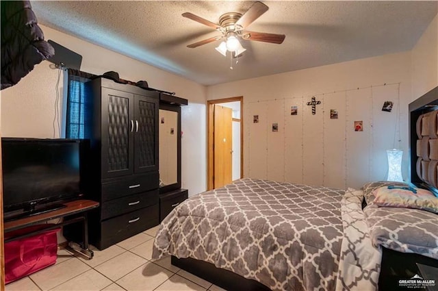 tiled bedroom with ceiling fan and a textured ceiling