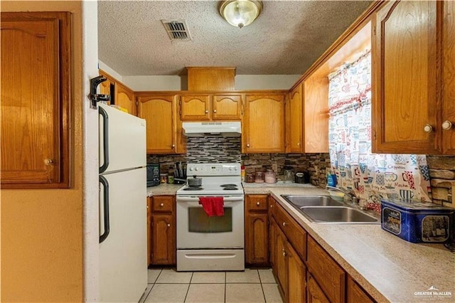 kitchen featuring sink, white appliances, light tile patterned floors, and a textured ceiling