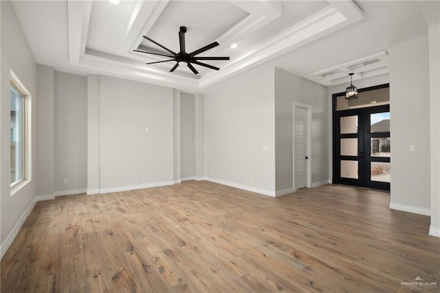 empty room featuring ceiling fan, wood-type flooring, and a tray ceiling