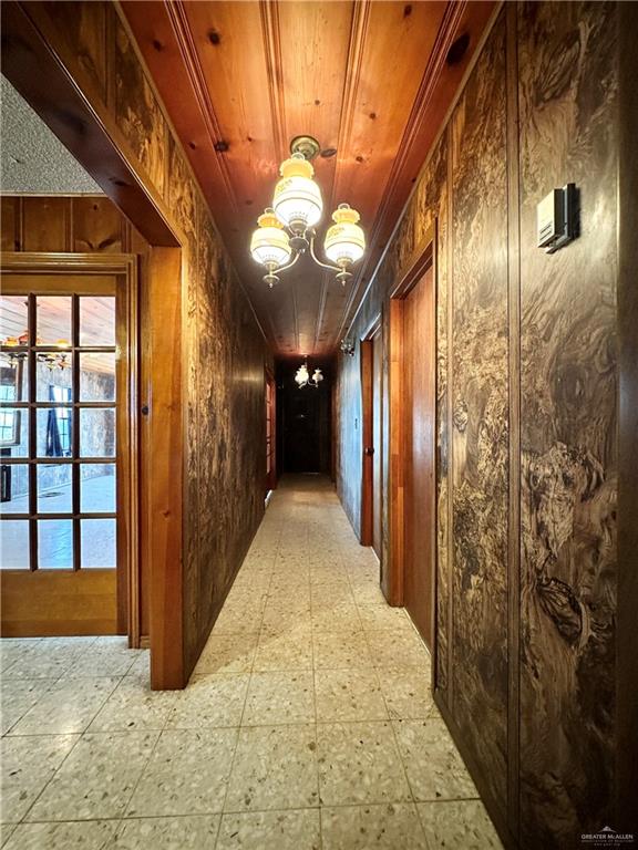 hall with an inviting chandelier and wooden walls