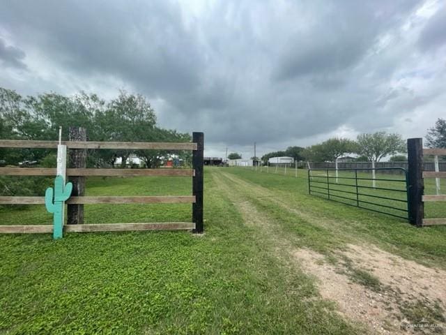 view of gate with a rural view and a lawn