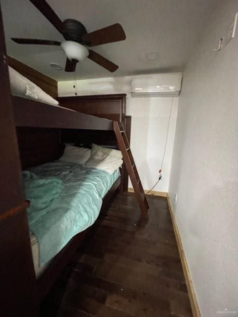 bedroom featuring dark hardwood / wood-style floors, ceiling fan, and an AC wall unit