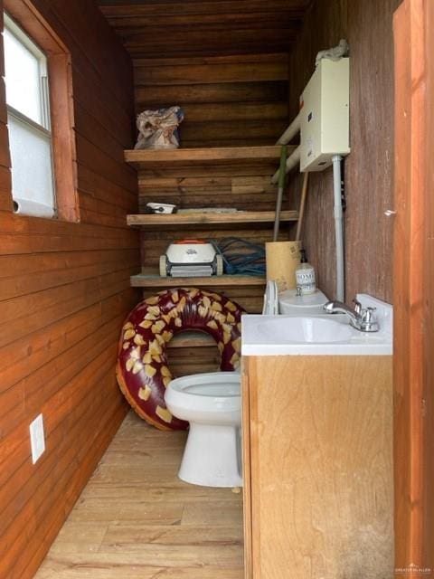 bathroom featuring vanity, wood walls, toilet, and wood-type flooring