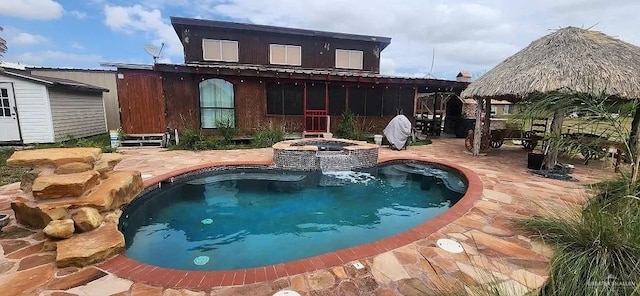 rear view of property with a gazebo, a patio area, and a pool with hot tub