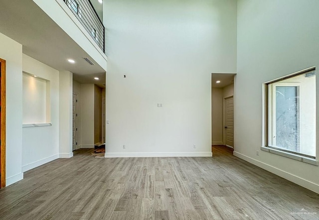 spare room with light wood-type flooring and a high ceiling